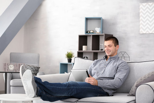 Young man with tablet on sofa at home