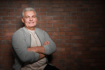 Handsome senior man in casual clothes on brick wall background