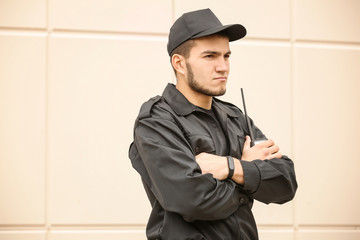 Male security guard with portable radio transmitter near light wall