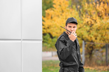 Male security guard using portable radio transmitter outdoors