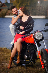 Obraz na płótnie Canvas stylish and trendy couple in love on a motorcycle flirting close-up on a background of late autumn in the park