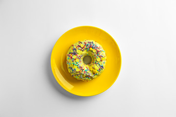 Yellow plate with tasty donut on white background