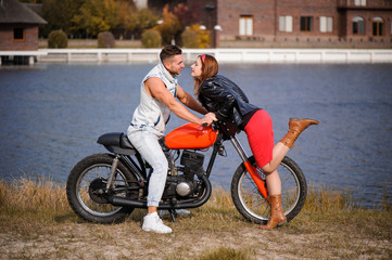 Plakat stylish and trendy couple in love on a lying motorcycle flirting close-up on a background of late autumn in the park