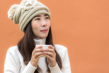 Smiling your asian women hand holding  white cup of coffee at the winter weather, colour full background.  Lifestyle Concept.