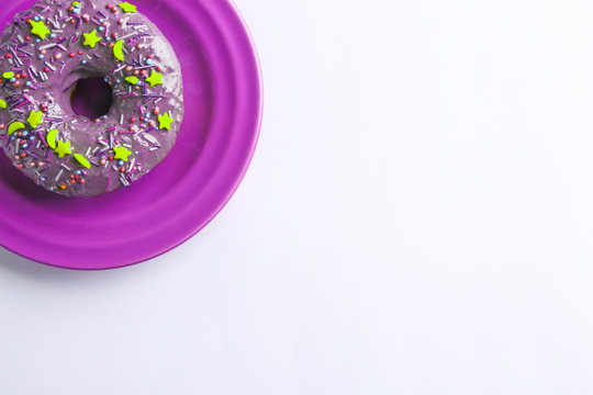 Plate with purple donut on white background