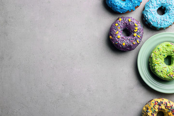Colorful donuts with sprinkles on grey background