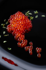 Red caviar on a black plate.