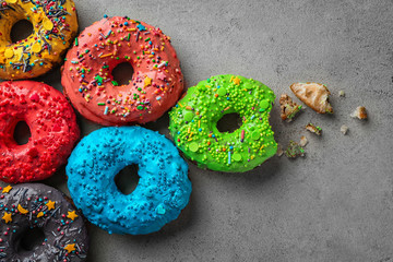 Colorful donuts with sprinkles on grey background