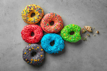Colorful donuts with sprinkles on grey background