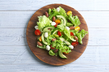 Board with delicious vegetable salad on wooden background