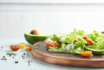 Wooden board with delicious vegetable salad on table, closeup