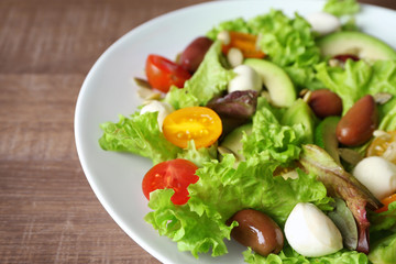Plate with delicious vegetable salad on wooden background, closeup