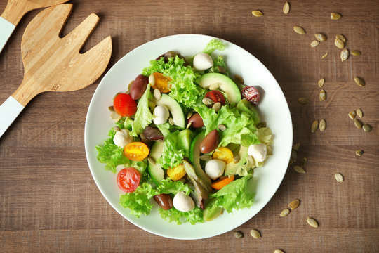 Plate with delicious vegetable salad on table, top view