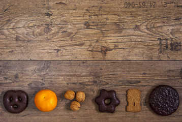 Lebkuchen, Mandarine, Nuesse und Spekulations in einer Reihe auf rustikalem Holzbodenhintergrund,...