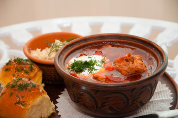 Ukrainian national cuisine, red borsch with meat and sour cream on a tray with bacon, garlic pampushkas and greens