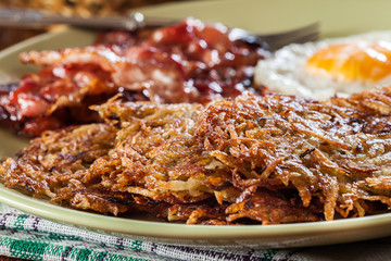 Hash browns. Potato pancakes with crispy fried bacon and fried egg