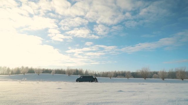 Men push broken van with engine problems in sunny winter day