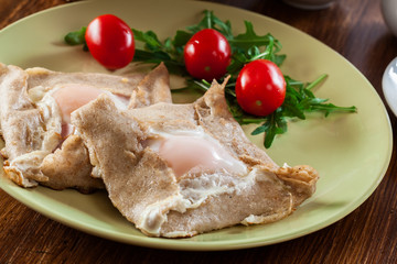 Crepes with ham, cheese and poached egg on a plate