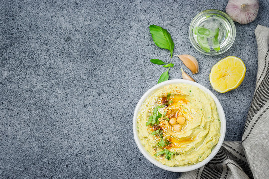 Basil pesto hummus in a bowl on stone or concrete background. Top view,space for text. 