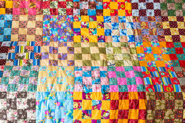 hobby, art, inspiration concept. close-up on delicately stitched old blanket with colored patchwork of patches forming square noticeable pattern and perfectly lining