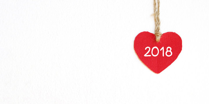 Red fabric heart shape with 2018 word hanging over white wall background, new year template banner