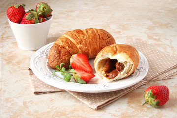 croissants with chocolate cream and berries strawberries on a light background