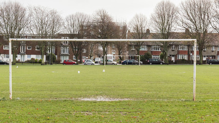 Waterlogged football pitch in  park with mud and water in goalmouth