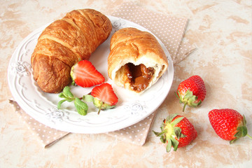 croissants with chocolate cream and berries strawberries on a light background