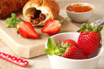 croissants with chocolate cream and berries strawberries on a light background