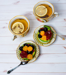 Fruit basket-cakes and cups with tea on a light background. View from above.