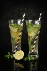 Drink mojitos with lime, mint, rum and soda in tall glasses