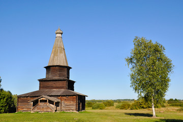 Fototapeta premium A wooden abandoned church near a birch tree in Veliky Novgorod on a summer evening, Russia.