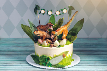 Children's holiday white cake decorated with dinosaurs in the Jurassic period jungle. Concept ideas...