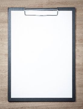 Blank clipboard on wooden background.