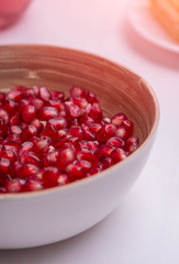 Full white bowl of fresh ripe red pomegranate on the white wood table. 