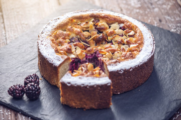 Homemade Christmas or New Year holiday berry pie with nuts on wooden table background. Concept of festive desserts