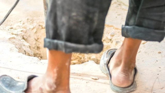 Worker using a jackhammer to break concrete at the construction site