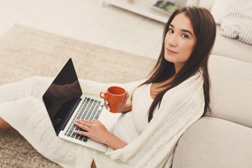 Cozy home. Girl in a plaid with a laptop and a cup