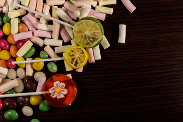 Colorful candies, lollipops and marshmallows on wooden table