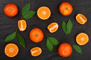 orange or tangerine with leaves on black stone background. Flat lay, top view. Fruit composition