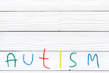 Childhood diseases. Word autism on white wooden background top view copyspace