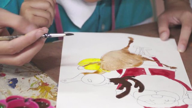 Mom Holds a Hand Her Daughter, Mom Teaches Daughter to Draw a santa claus