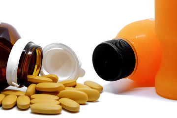 Pills of vitamin C and fresh orange juice bottle on white background, medical and healthcare concept