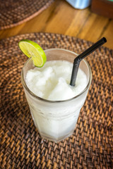 A glass with fresh organic lime juice on a wooden background. Bali island, Indonesia.