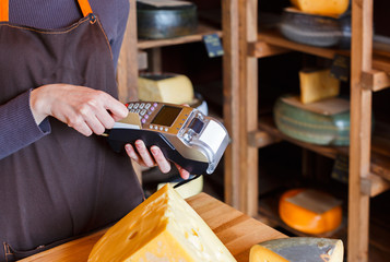Customer paying for order of cheese in grocery shop.