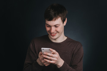 A man looks at a mobile phone screen and dials the message , the portrait of a man close up in Studio on dark background