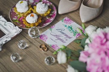 Golden rings of the newlyweds on the table among the flowers, shoes an