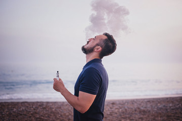Man with beard smoking electronic sigarette outdoor