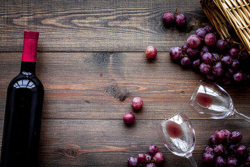 Drink wine. Bottle, glaas and grape on dark wooden background top view copyspace