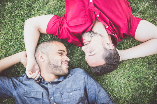 Happy gay couple lying down on the grass